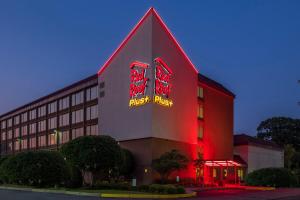 a building with red and yellow neon signs on it at Red Roof Inn PLUS+ Boston - Woburn/ Burlington in Woburn