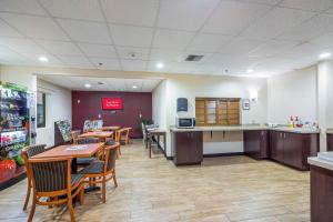 a dining room with tables and chairs and a kitchen at Red Roof Inn Ocala in Ocala