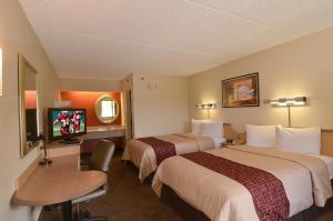 a hotel room with two beds and a desk and a tv at Red Roof Inn San Antonio Airport in San Antonio