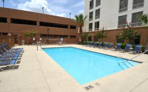 une grande piscine avec des chaises et un bâtiment dans l'établissement Red Roof Inn PLUS+ San Antonio Downtown - Riverwalk, à San Antonio