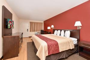 a bedroom with a large bed and a red wall at Red Roof Inn Marietta in Marietta