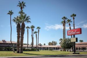 a sign for a hotel with palm trees in front of a building at Red Roof Inn Blythe in Blythe