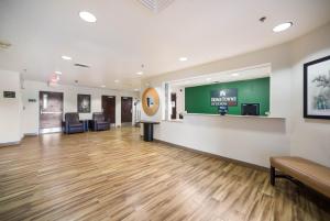a large lobby with a waiting room with wooden floors at HomeTowne Studios by Red Roof St. Louis - Airport/N Lindbergh in Hazelwood