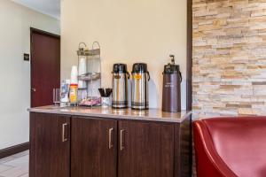 a counter with two thermos on it with a red chair at Red Roof Inn Dry Ridge in Dry Ridge