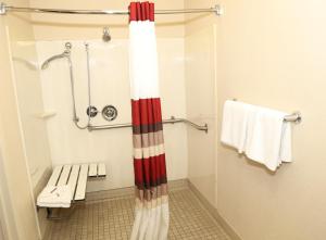 a bathroom with a shower with a bench and towels at Red Roof Inn Enfield in Enfield