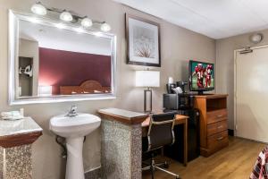 a bathroom with a sink and a desk with a mirror at Red Roof Inn Morton Grove in Morton Grove