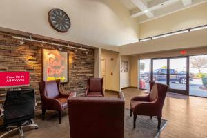 uma sala de espera com cadeiras e um relógio numa parede de tijolos em Red Roof Inn PLUS+ El Paso East em El Paso