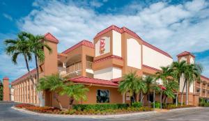 a building with palm trees in front of a street at Red Roof Inn PLUS+ & Suites Naples Downtown-5th Ave S in Naples