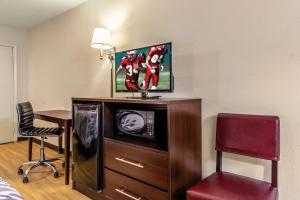 a hotel room with a tv and a desk with a chair at Red Roof Inn Scottsburg in Scottsburg