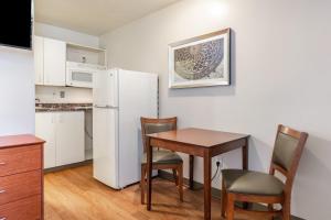 a small kitchen with a table and a refrigerator at HomeTowne Studios by Red Roof Louisville in Louisville