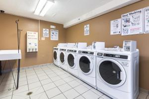 a laundry room with three washing machines and signs on the wall at HomeTowne Studios by Red Roof Louisville in Louisville