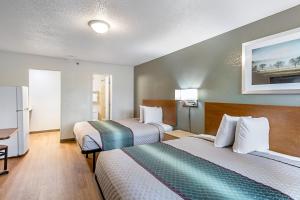 a hotel room with two beds and a desk at HomeTowne Studios by Red Roof Atlanta – Lawrenceville in Lawrenceville