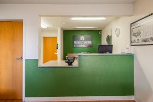 a front desk of a honolulu clinic with a green wall at HomeTowne Studios by Red Roof Denver - Airport/Aurora in Aurora