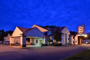 a hotel with a neon sign in a parking lot at Red Roof Inn Sandusky - Milan in Milan