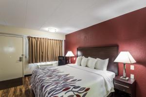 ein Hotelzimmer mit einem großen Bett und roten Wänden in der Unterkunft Red Roof Inn Milwaukee Airport in Oak Creek