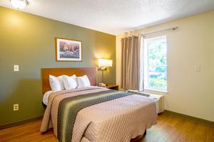 a bedroom with a large bed with a window at HomeTowne Studios by Red Roof Chicago - Waukegan in Waukegan