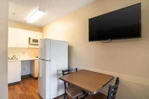 a kitchen with a table and a white refrigerator at HomeTowne Studios by Red Roof Chicago - Waukegan in Waukegan