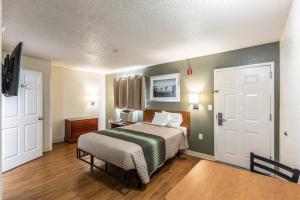 a bedroom with a bed with a green blanket at HomeTowne Studios by Red Roof Atlanta - Chamblee in Atlanta +17 photos