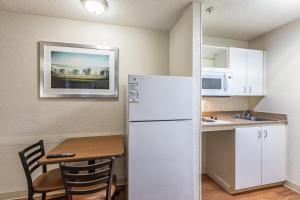 a kitchen with a white refrigerator and a table at HomeTowne Studios by Red Roof Atlanta - Chamblee in Atlanta