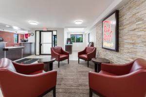 a waiting room at a dental office with red chairs and tables at Red Roof Inn PLUS+ Columbus - Worthington in Columbus
