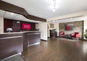 a lobby with a waiting room with red chairs and a tv at Red Roof Inn Chicago-OHare Airport Arlington Hts in Arlington Heights