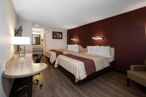 a hotel room with two beds and a desk at Red Roof Inn Indianapolis - Greenwood in Greenwood