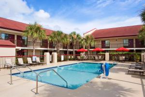 a pool at a hotel with tables and chairs at Red Roof Inn PLUS+ Mt Pleasant - Patriots Point in Charleston