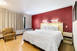 ウェストパームビーチにあるRed Roof Inn PLUS+ West Palm Beachの大きなベッドと椅子のあるホテルの部屋