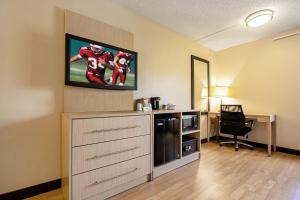 a room with a tv on a wall with a desk at Red Roof Inn PLUS+ West Palm Beach in West Palm Beach