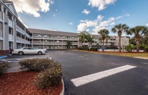 a car parked in a parking lot in front of a building at HomeTowne Studios by Red Roof Orlando South in Orlando