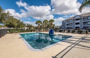 uma piscina num resort com cadeiras e um edifício em HomeTowne Studios by Red Roof Orlando South em Orlando