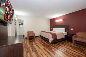 a hotel room with a bed and a flat screen tv at Red Roof Inn Starkville - University in Starkville