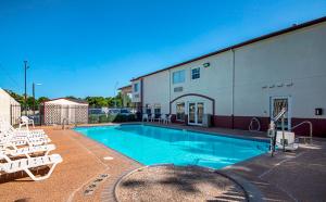 a swimming pool with white chairs and a building at Red Roof Inn San Marcos in San Marcos