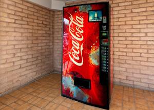 un distributore automatico di coca cola seduto contro un muro di mattoni di Red Roof Inn Monroe a Monroe