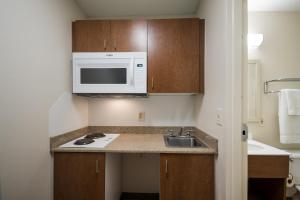a small kitchen with a sink and a microwave at HomeTowne Studios by Red Roof Seattle - Kent/Des Moines in Des Moines