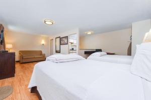 a hotel room with two beds and a couch at Red Roof Inn PLUS+ & Suites Guilford in Guilford