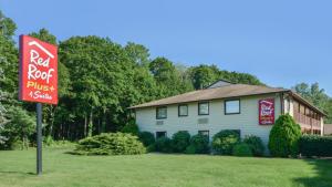 a house with a red roost sign in front of it at Red Roof Inn PLUS+ & Suites Guilford in Guilford