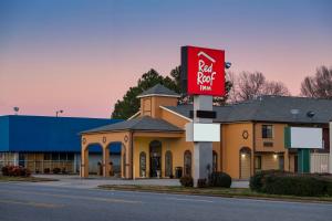 a building with a red sign in front of it at Red Roof Inn Muscle Shoals in Muscle Shoals