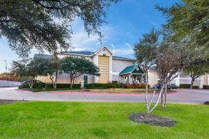 a house with a tree in the front yard at HomeTowne Studios by Red Roof Dallas - North Addison - Tollway in Addison