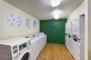 a laundry room with white machines and a green wall at HomeTowne Studios by Red Roof Dallas - North Addison - Tollway in Addison