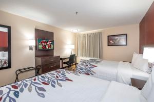 a hotel room with two beds and a desk at Red Roof Inn Raleigh Southwest - Cary in Cary
