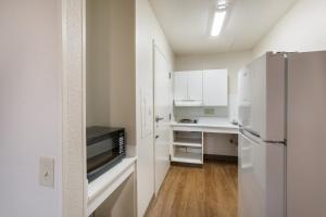  La cuisine est équipée de placards blancs et d'un réfrigérateur. dans l'établissement HomeTowne Studios by Red Roof Detroit - Livonia, à Livonia