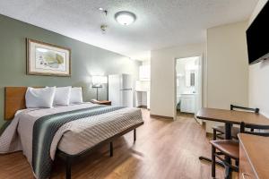 a bedroom with a bed and a table and a kitchen at HomeTowne Studios by Red Roof Atlanta NE – Norcross South in Norcross