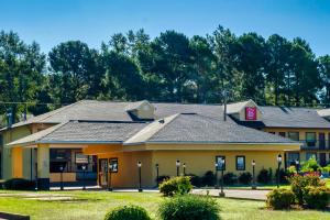 un grupo de edificios con árboles en el fondo en Red Roof Inn Columbus, MS, en Columbus