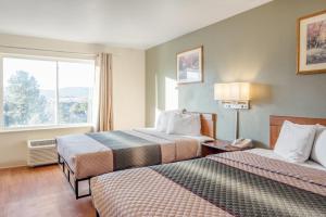 a hotel room with two beds and a window at HomeTowne Studios by Red Roof Colorado Springs - Airport in Colorado Springs