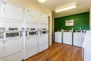 een wasruimte met witte wasmachines en een groene muur bij HomeTowne Studios by Red Roof - Atlanta NE - Peachtree Corners in Norcross
