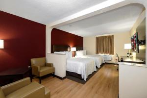 a hotel room with two beds and a chair at Red Roof Inn PLUS+ & Suites Opelika in Opelika +43 photos