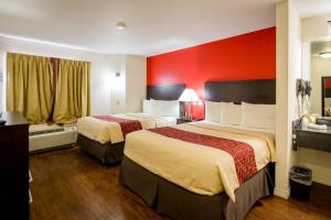 a hotel room with two beds and a red wall at Red Roof Inn Austin - Round Rock in Round Rock