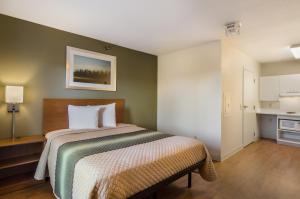 a bedroom with a bed and a kitchen at HomeTowne Studios by Red Roof Denver - Glendale/ Cherry Creek in Denver