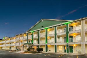 un gran edificio de apartamentos con iluminación verde en un aparcamiento en HomeTowne Studios by Red Roof Denver - Glendale/ Cherry Creek en Denver